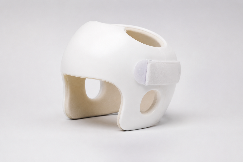 White infant cranial helmet with ventilation openings and an adjustable strap.